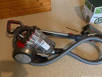 Full view of Hoover canister vacuum featuring hose, wand, and suction head on beige carpet.
