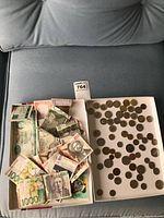Tray with assorted international paper money and coins in cardboard boxes