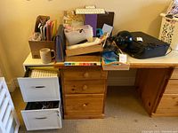 Wide shot of wooden filing cabinet with drawers, file folders, wooden trays, black desk lamp, and Apple keyboard on desk.