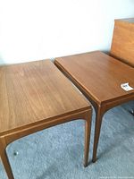 Two matching teak side tables side by side on carpet