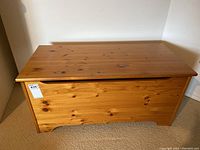 Front view of closed pine wooden trunk showing clean and polished wood surface with visible wood grain and knots.