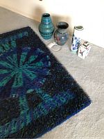 Partial view of shag rug on carpeted floor with all four vases arranged above its corner