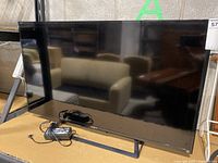 Front view of Sony 40-inch TV on stand with power adapter included, no remote visible.
