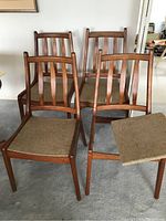 Four teak chairs grouped together, front view