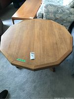 Top view of the octagonal teak veneer coffee table showing the overall shape and surface with minor wear.