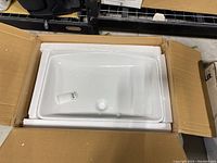 White rectangular ceramic vessel sink in original cardboard box with white styrofoam padding. View from above shows basin interior and drain hole.