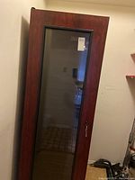 Front view of the Vintage Keeper wine cellar showing wooden frame with glass door and visible lock and key attached.
