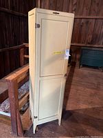 External view of tall cream-colored Napanee Dutch Kitchenet cabinet with single door closed.