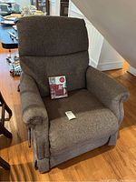 Front view of gray La-Z-Boy recliner with cleaning kit on seat, showing general condition and shape.