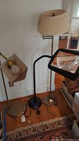 View of three floor pole lamps grouped together on the floor, showing base materials and overall condition.