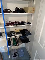 Shelf with multiple formal accessories including belts, shoes, ties, cummerbunds, and dress shirts.