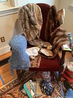 Photo of multiple vintage mink stoles draped over a chair, a blue knit scarf, fabric bag, and a small pile of assorted patterned bandanas laid out on the floor.