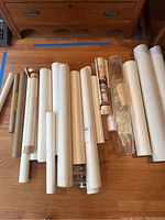 Rolled posters and prints on hardwood floor showing multiple paper tubes and partially unrolled items