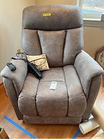 Front view of recliner with wired remote on left arm and small decorative pillow on seat