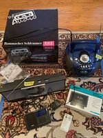 Photo showing the four electronic devices including the Hammacher Schlemmer music center with box, Zenith clock radio box, Grundig Eton radio, and Emerson CD player.