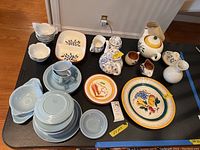 Full lot arranged on a black table showing various ceramic items including lotus bowls, plates, teapots, and pitchers.