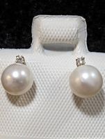 Front view of pearl and diamond stud earrings on white textured holder.
