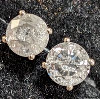 Two round diamond stud earrings on black velvet background