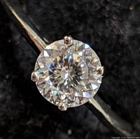 Front view of round moissanite in four-prong setting on plain band