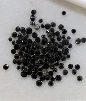 Close-up view of many small round black diamonds on white background.