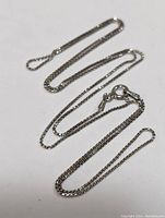 Silver chain necklace laid out showing full length and clasp detail.