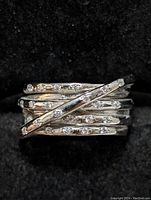 Close-up of silver cubic zirconia ring showing intertwined multi-band design and hammered texture with stones