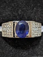 Close up front view of sapphire and side pavé clear stones on rhodium plated sterling silver ring