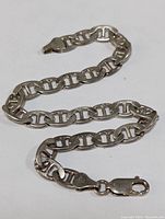 Photo shows the full length of the sterling silver bracelet with linked chain and lobster clasp closure laid out on a white background.