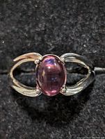 Top-down close-up view of sterling silver ring showcasing the oval purple cabochon gemstone and split band design.