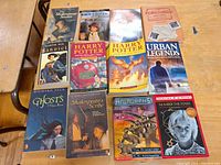 Photo of 11 tween and young adult books laid out on a wooden surface showing titles including Harry Potter, Shakespeare's Scribe, Urban Legends, and others.