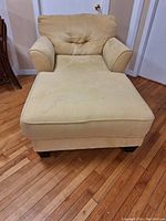 Front view of beige upholstered chaise lounge showing overall shape, cushion, armrests, and legs