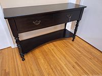 Front and side view of black wood console table showing its dimensions and style