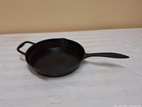Full view of the black Lagostina cast iron frying pan showing the cooking surface and handles.