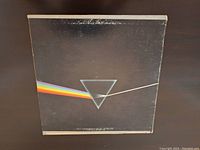 Front cover of Pink Floyd The Dark Side of the Moon vinyl LP showing the prism and light dispersion rainbow on black background with some surface wear.