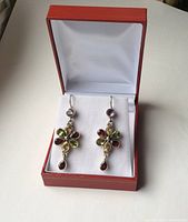 Pair of sterling silver dangle earrings with colored stones displayed in an open red jewelry box against a white background.