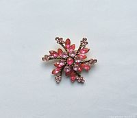 Front view of the pink and mauve rhinestone snowflake brooch on a white background, showing detail and overall shape.