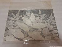 Front view of the handmade paper pulp painting with leaves motif in white and gray.