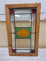Full frontal view of the wood framed stained glass showing the colored glass design and natural wood frame.