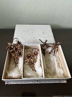 Three sterling silver brooches in a box, two dancer figurines and one floral design brooch