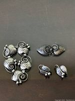 Top-down view of bracelet, brooch, and earrings on dark surface