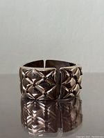 Front view showing wide bracelet with raised quilted design and gold-tone ball accents.