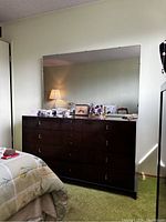 Front view of the dresser with 14 drawers and large attached mirror reflecting the room.