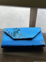 Closed blue fabric case with floral embroidery on a glass surface