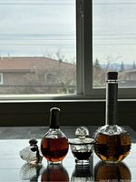 First image showing both perfumes with window background for lighting and reflection