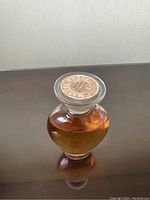 Vintage Marcel Rochas perfume bottle filled with amber perfume liquid with metallic branded cap on stopper top.