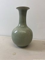 Full view of a pale celadon porcelain vase with a rounded base and tall neck
