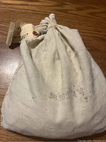 Full view of the cotton drawstring bag showing the bag shape, drawstring tie, and stamped number on fabric.