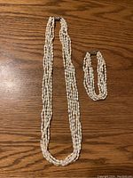 Full view of the freshwater pearl necklace and matching bracelet displayed on a wooden surface.