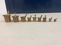 Image showcasing nine brass mortar and pestle sets arranged in a row from largest to smallest.