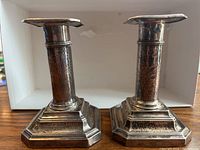 Pair of silver candle holders with hammered texture on columns, stepped bases, and square tops.